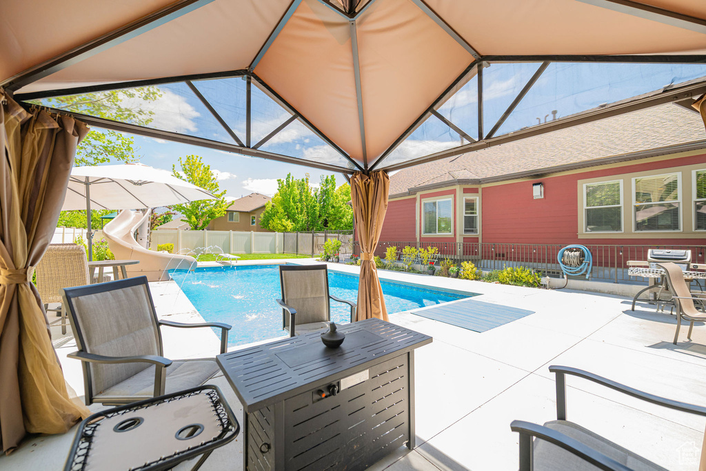 View of pool featuring a water slide, a patio, and fence