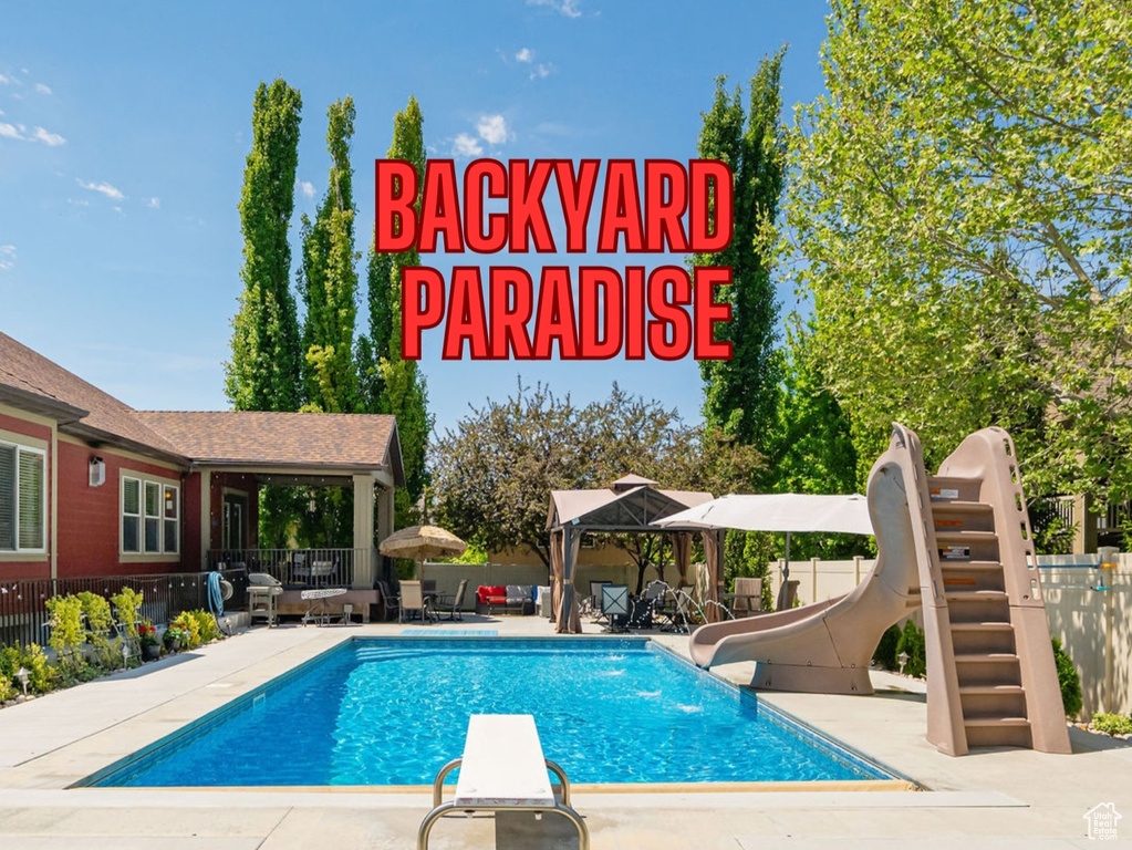 View of swimming pool featuring a water slide, a patio, a diving board, and a gazebo