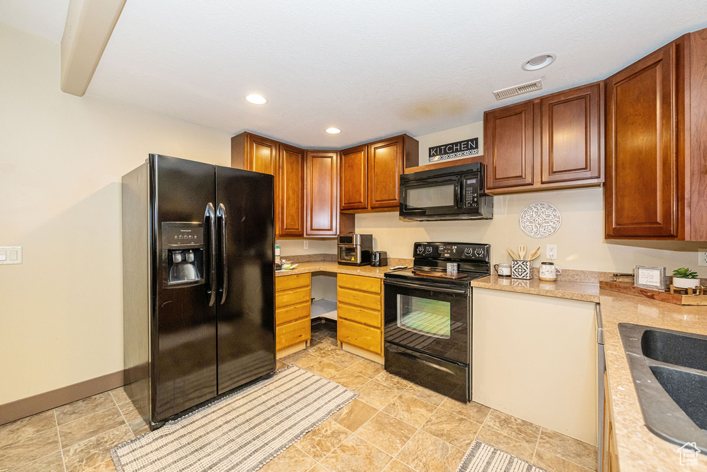 Kitchen featuring black appliances, light countertops, a sink, recessed lighting, and baseboards