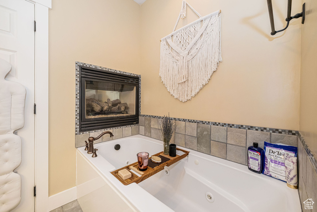 Full bath featuring a tub with jets, baseboards, and a multi sided fireplace