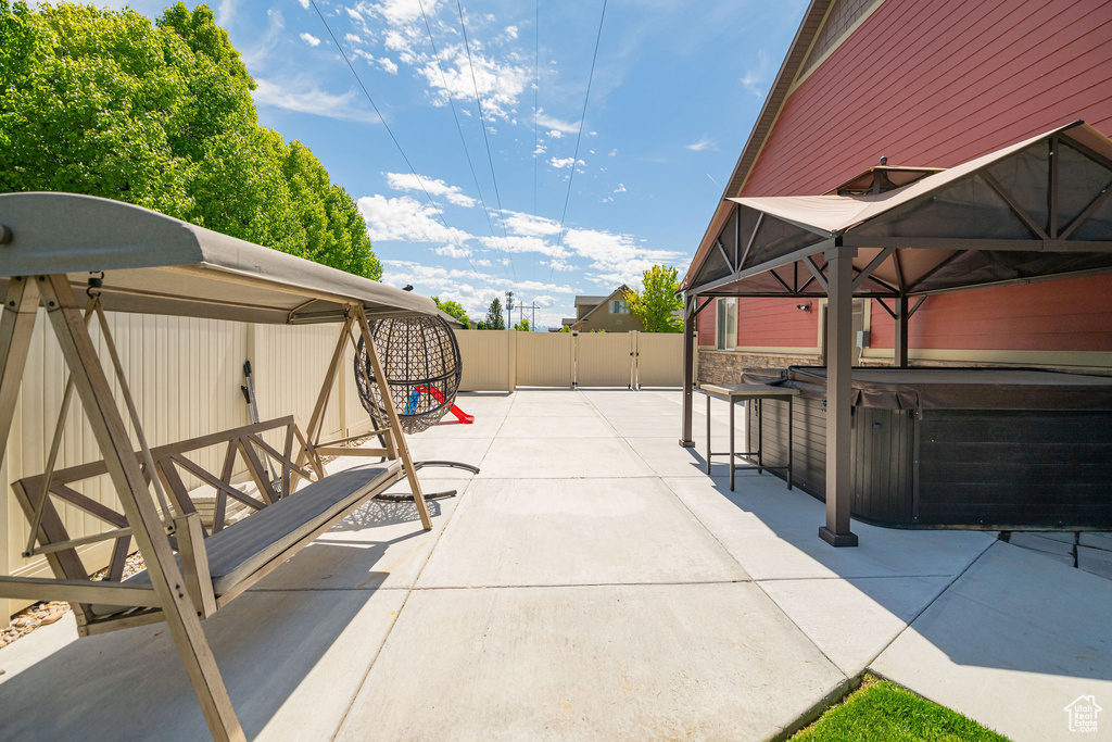 View of patio / terrace featuring a hot tub, fence, and a gate