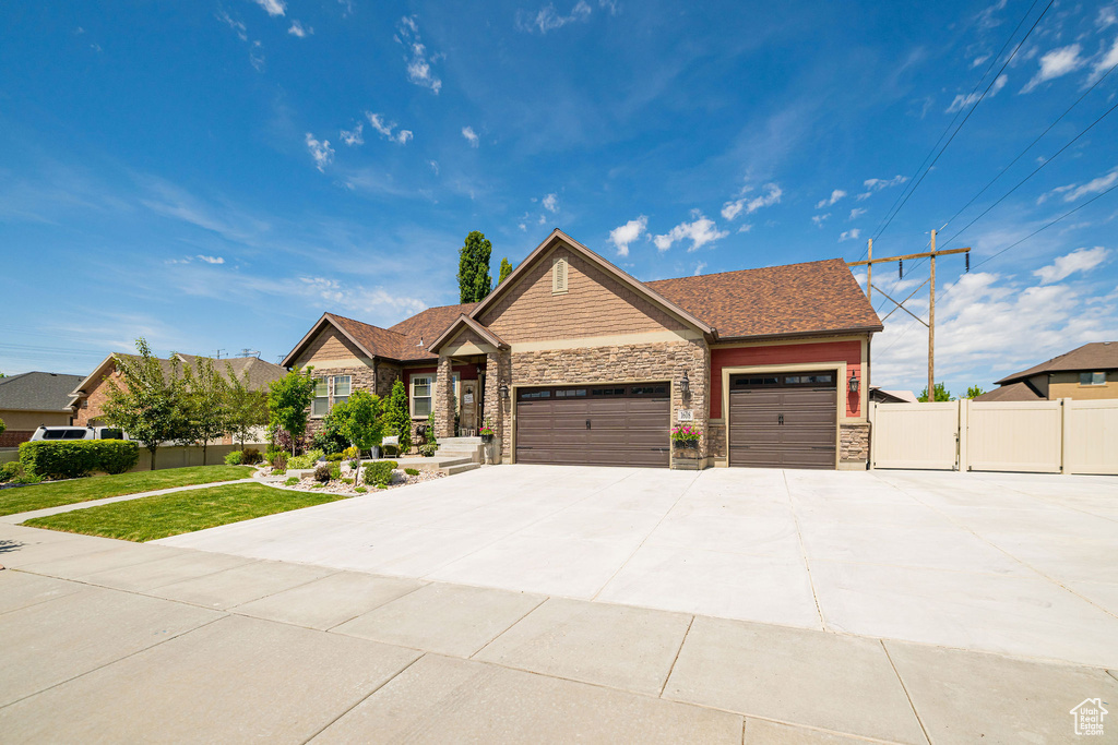 Craftsman inspired home with stone siding, an attached garage, and driveway
