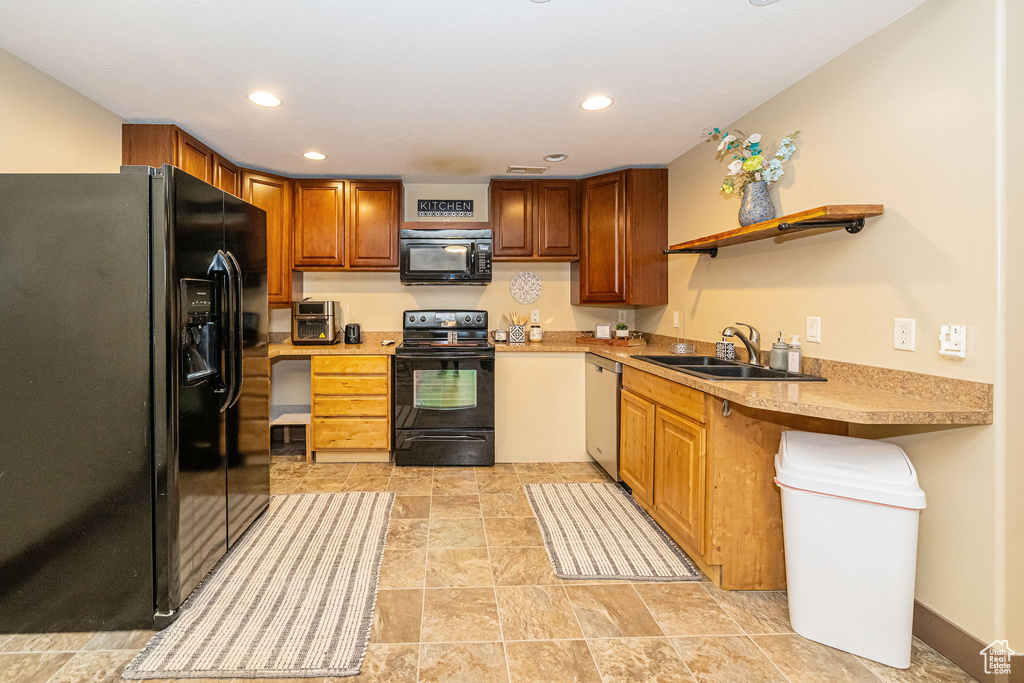 Kitchen featuring black appliances, a sink, light countertops, recessed lighting, and brown cabinetry
