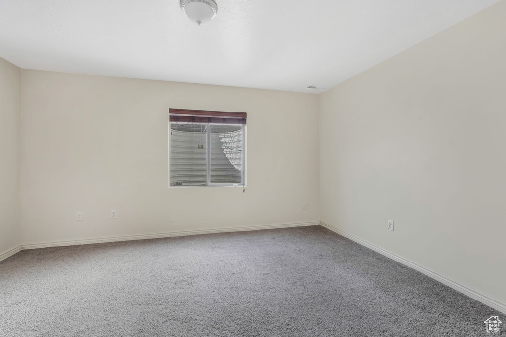 Carpeted spare room featuring baseboards