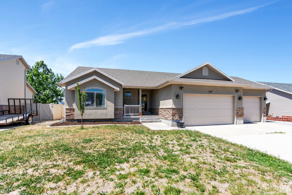 Ranch-style house with stucco siding, stone siding, driveway, and an attached garage
