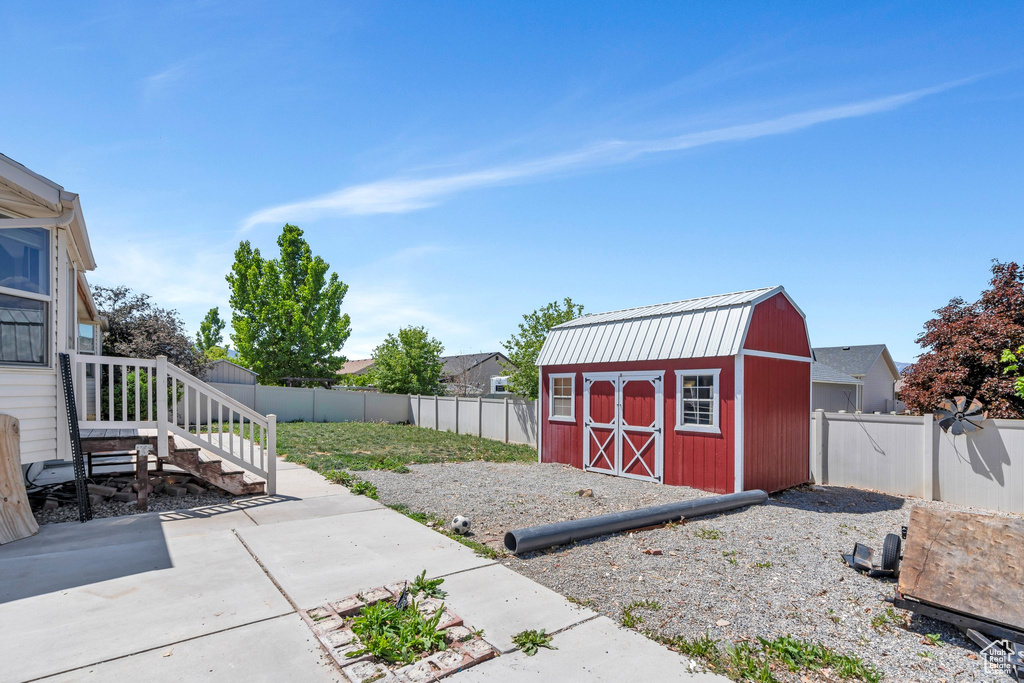 Fenced backyard featuring a storage shed, an outbuilding, and a patio area