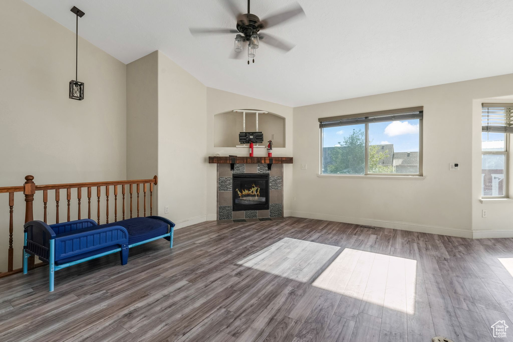 Living area with lofted ceiling, wood finished floors, a ceiling fan, and plenty of natural light