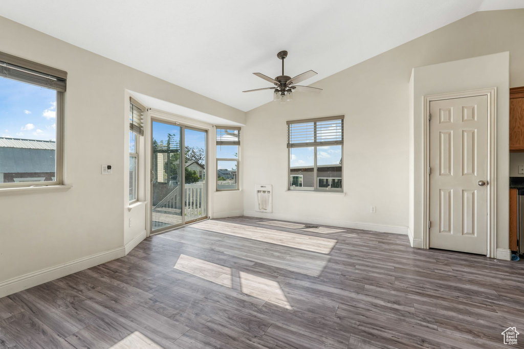 Unfurnished room with vaulted ceiling, ceiling fan, dark wood-style floors, baseboards, and heating unit