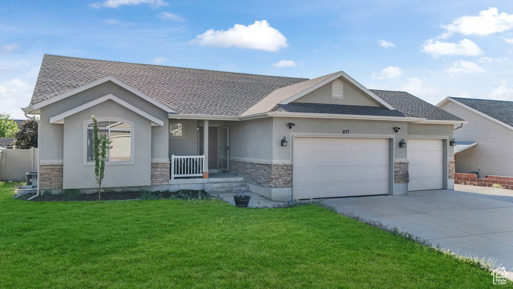 Single story home featuring stone siding, stucco siding, an attached garage, a shingled roof, and driveway