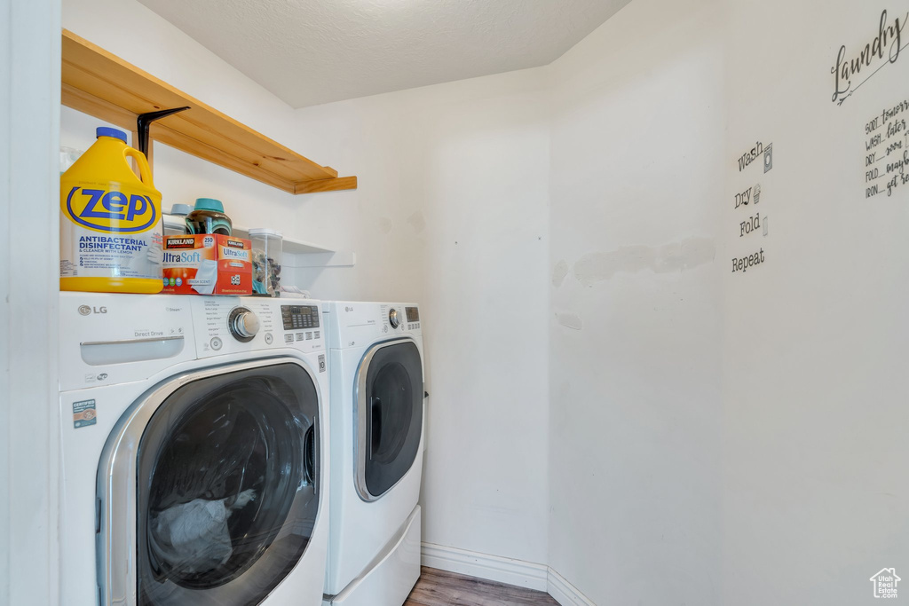 Clothes washing area with separate washer and dryer, wood finished floors, and baseboards