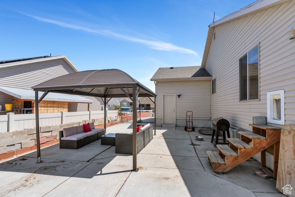 View of patio with an outdoor hangout area, a gazebo, and fence