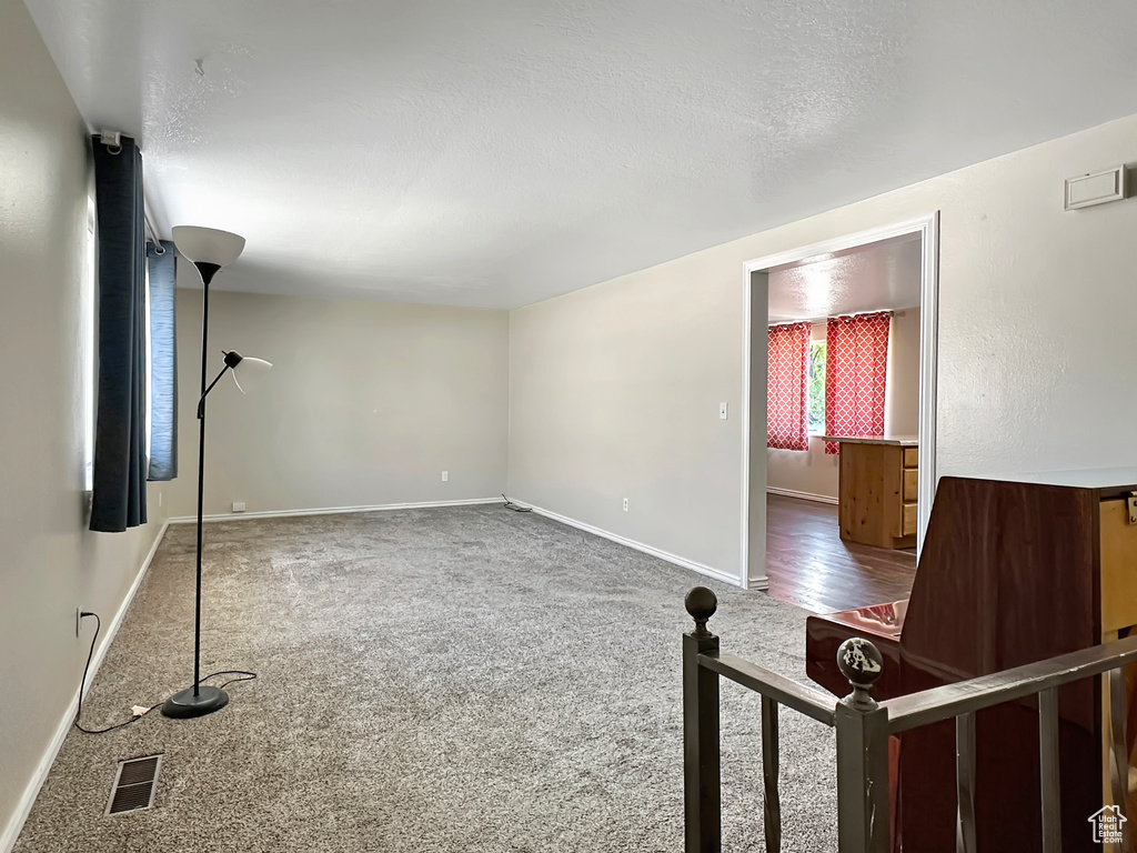 Unfurnished living room with carpet, baseboards, and a textured ceiling