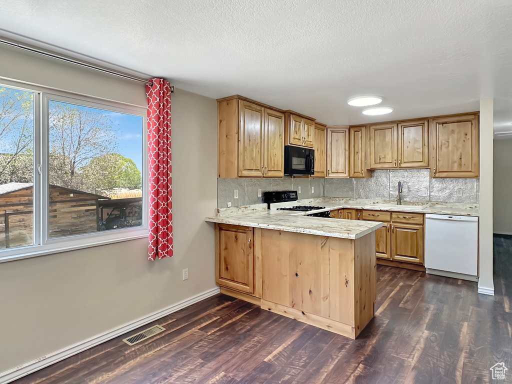 Kitchen featuring black microwave, dishwasher, a sink, range with gas stovetop, and dark wood-type flooring