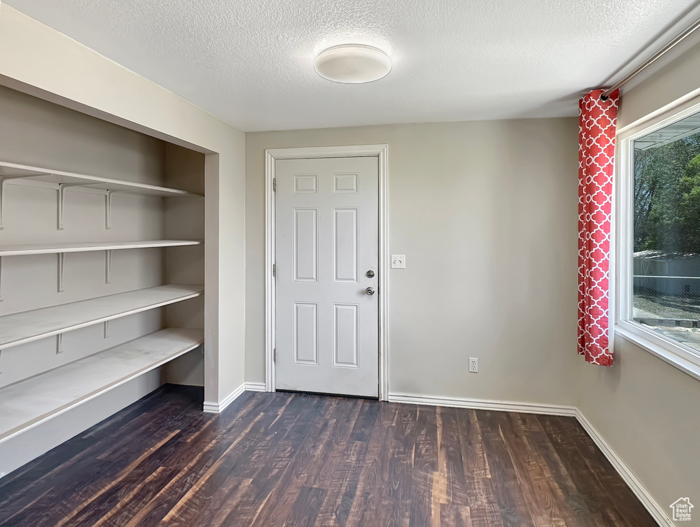 Entrance foyer featuring dark wood-type flooring, a textured ceiling, and baseboards