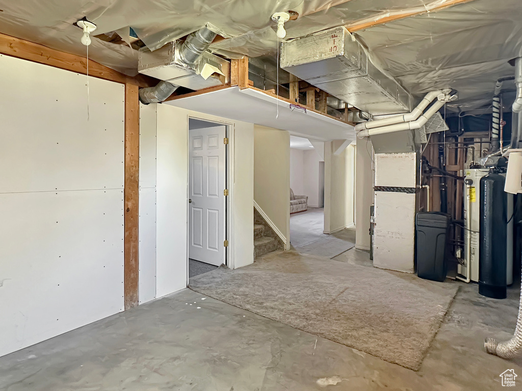 Unfinished below grade area featuring stairway and a water softener system