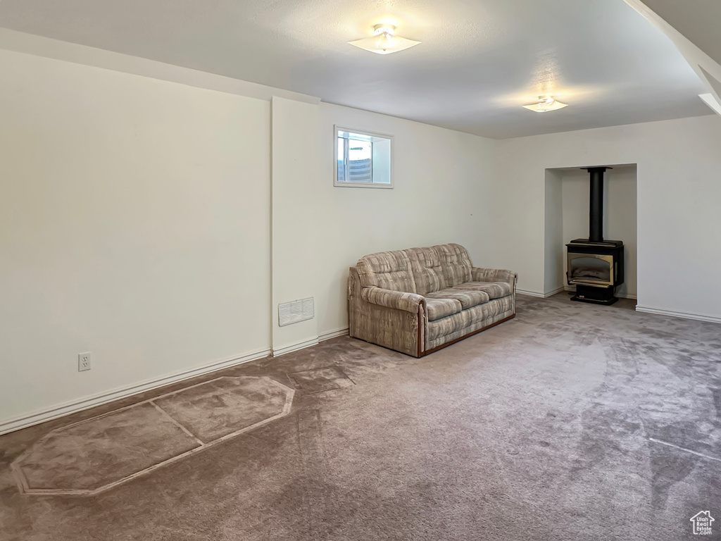 Living area with a wood stove, carpet floors, and baseboards