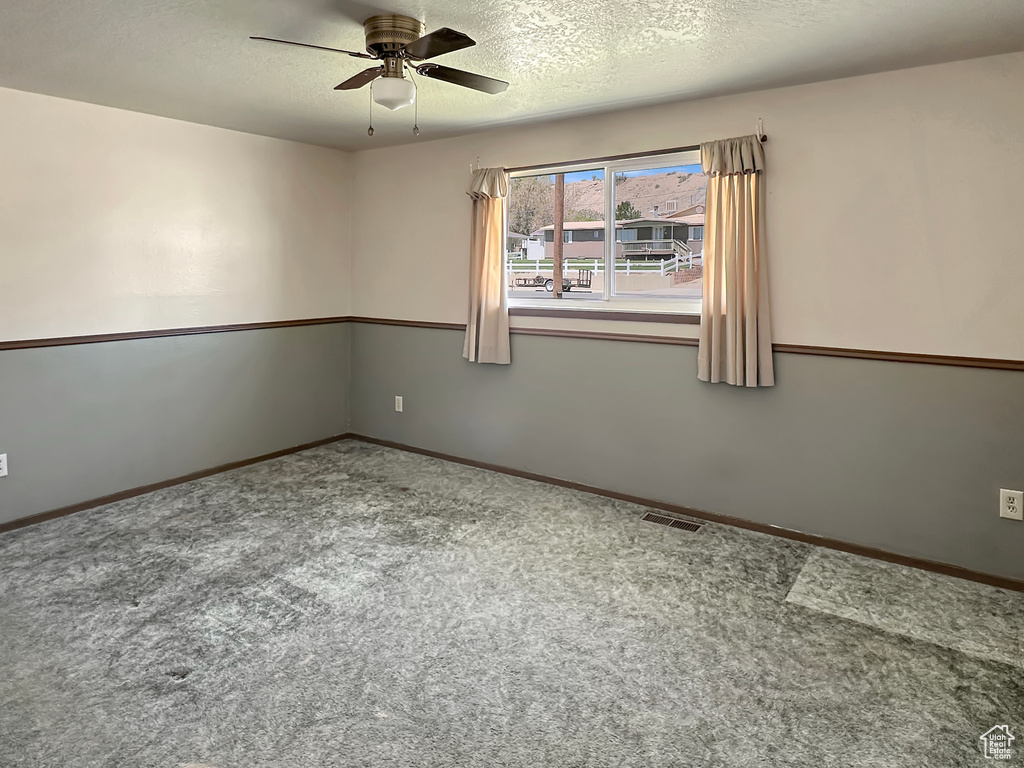 Unfurnished room with ceiling fan, carpet floors, a textured ceiling, and baseboards