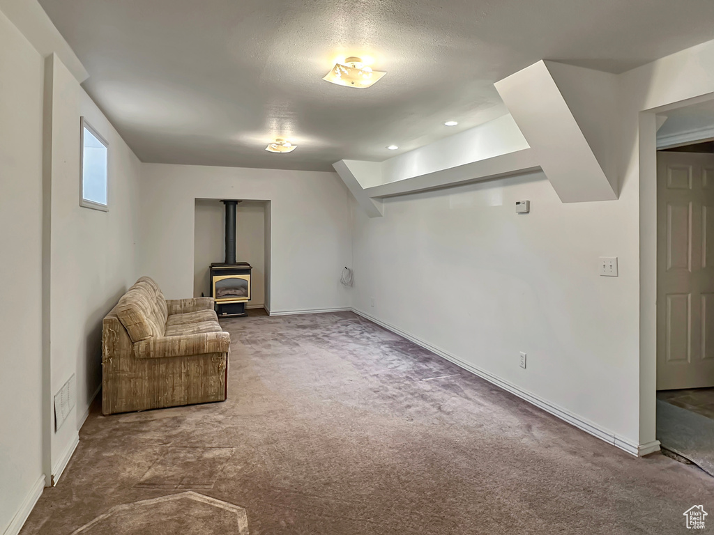 Unfurnished room with a wood stove, carpet floors, and baseboards