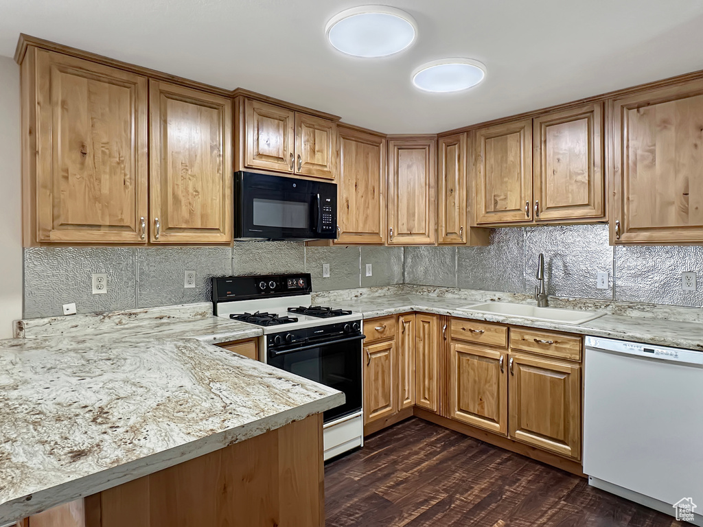 Kitchen with black microwave, white dishwasher, range with gas stovetop, a sink, and decorative backsplash