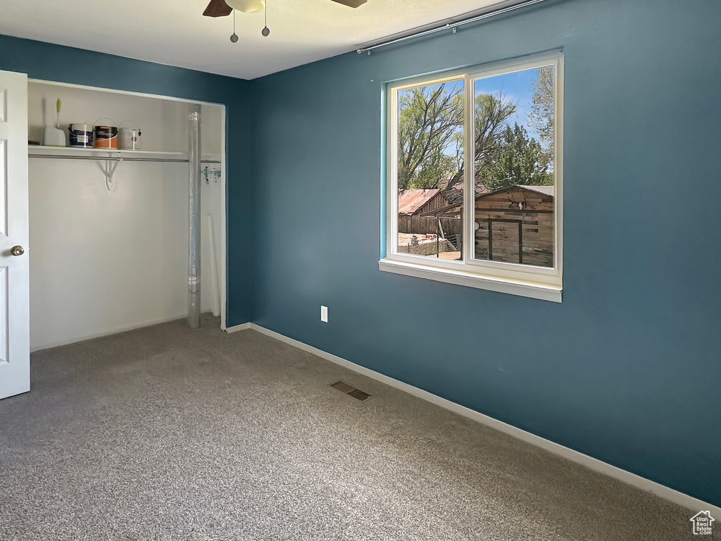 Unfurnished bedroom featuring a closet, carpet floors, baseboards, and a ceiling fan