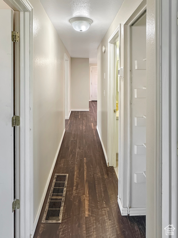 Corridor featuring dark wood-style flooring and baseboards