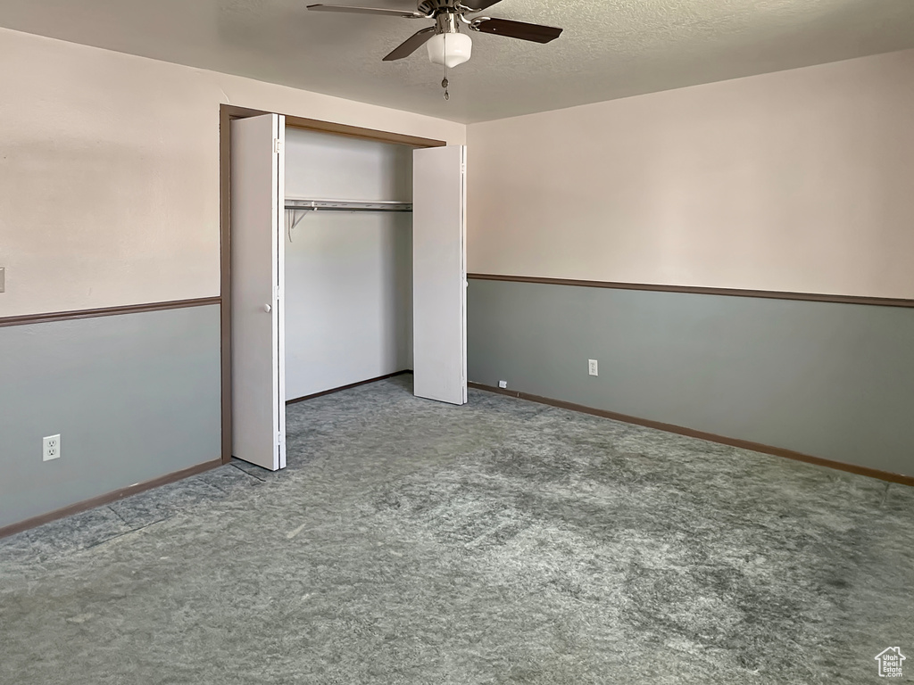 Unfurnished bedroom with carpet, a closet, baseboards, and a ceiling fan