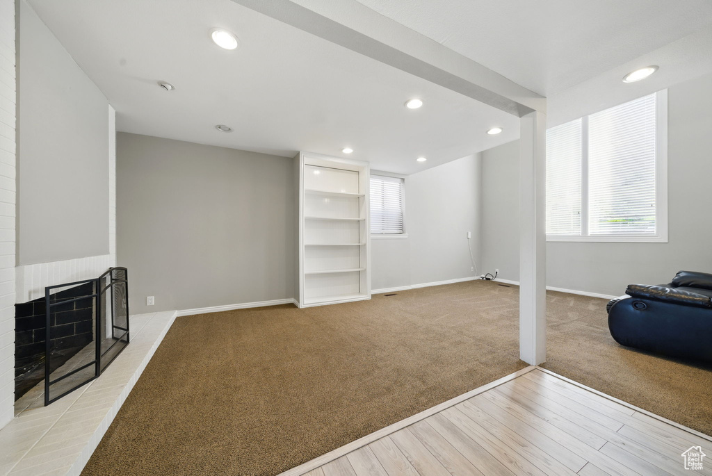 Unfurnished living room featuring light carpet, light wood-style floors, baseboards, recessed lighting, and a fireplace with raised hearth