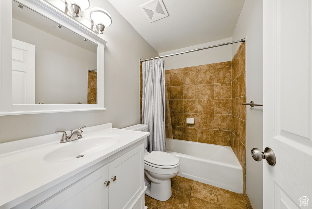 Bathroom featuring toilet, vanity, shower / bathtub combination with curtain, and tile patterned floors
