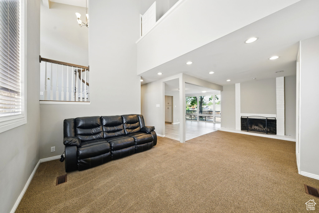 Carpeted living room with a chandelier, baseboards, recessed lighting, and a fireplace with raised hearth