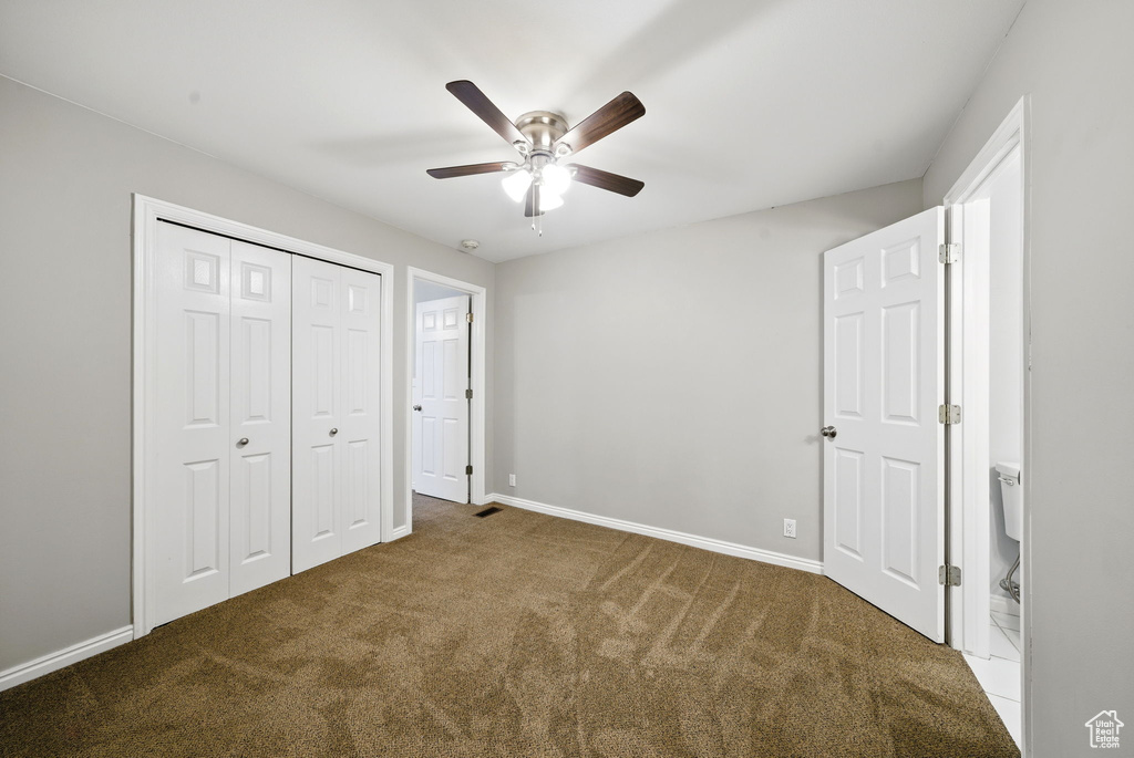 Unfurnished bedroom with carpet, a closet, baseboards, and ceiling fan