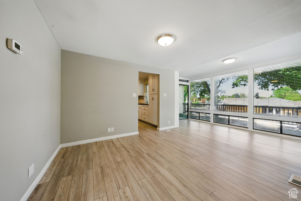 Spare room featuring light wood-style flooring, a wall of windows, and baseboards
