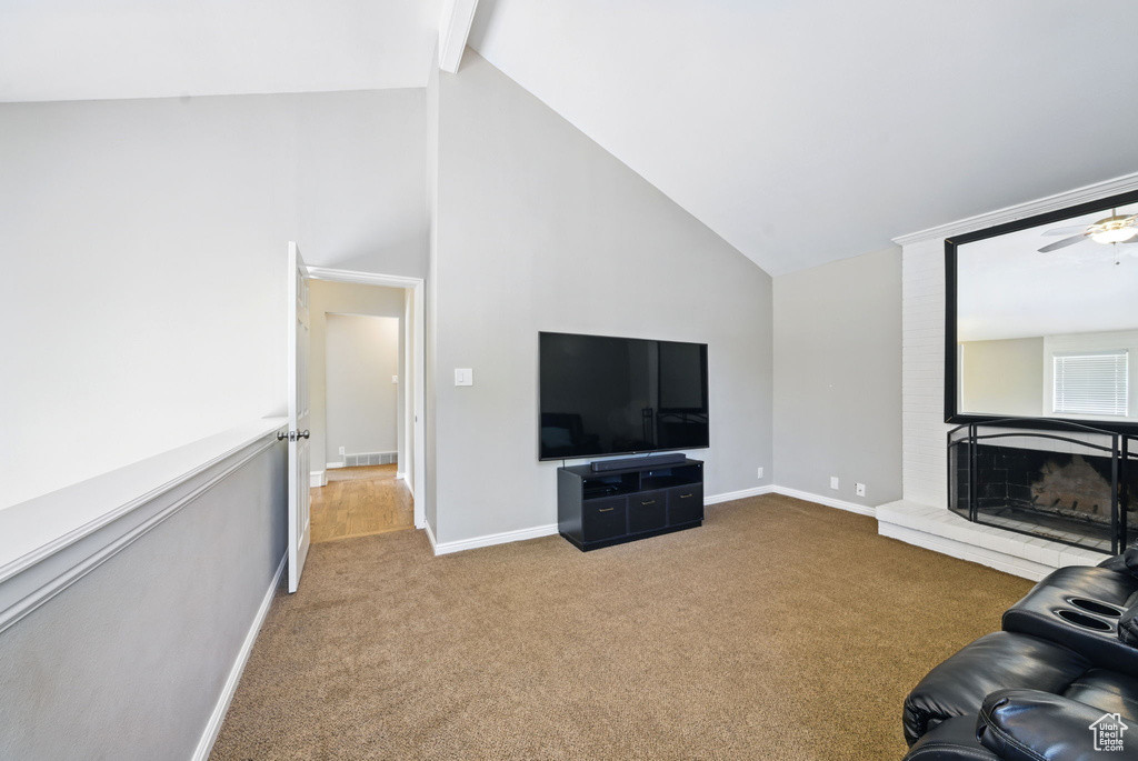 Unfurnished living room featuring carpet floors, high vaulted ceiling, baseboards, ceiling fan, and a brick fireplace