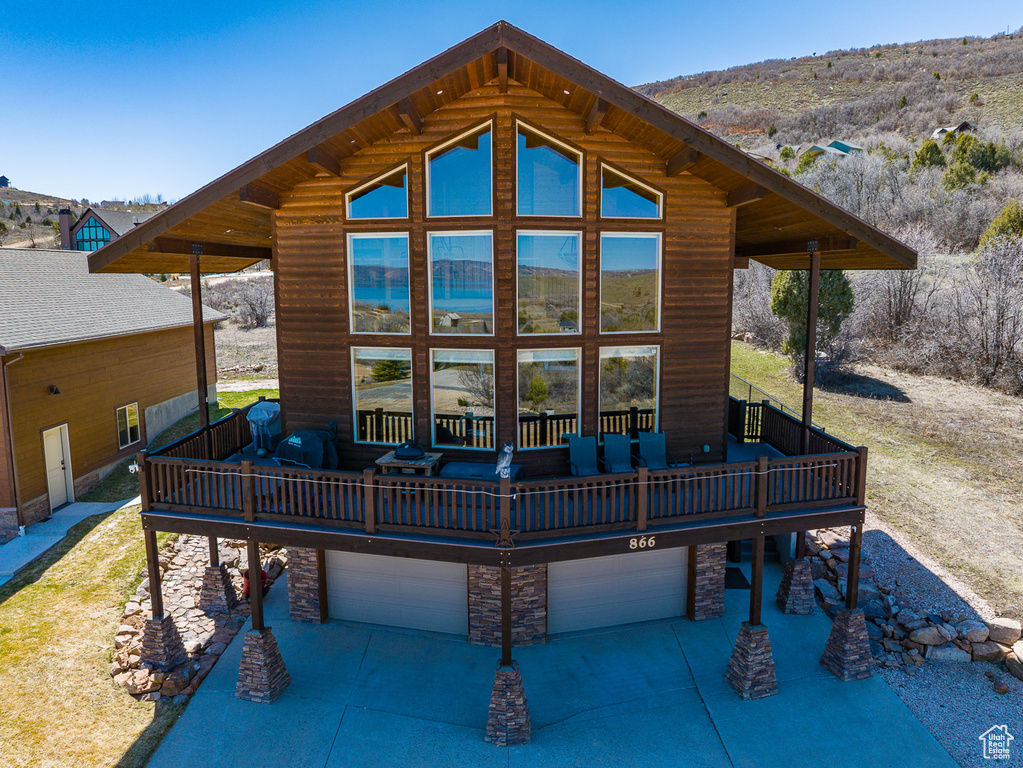 Rear view of house with an attached garage, a deck, and driveway