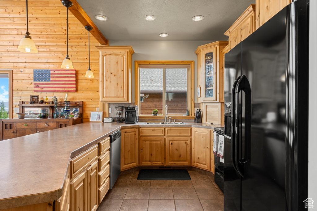Kitchen featuring black fridge, a sink, dishwasher, a peninsula, and light brown cabinetry
