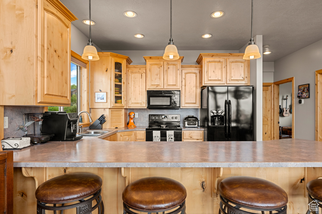 Kitchen featuring black appliances, light brown cabinetry, a sink, backsplash, and recessed lighting