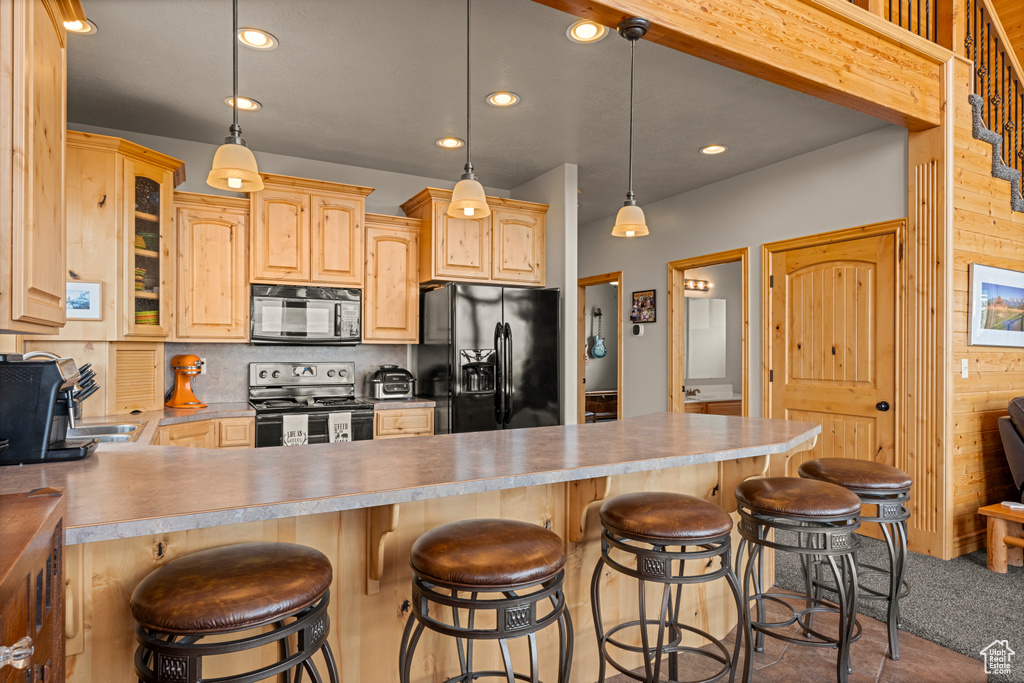 Kitchen featuring black appliances, light brown cabinetry, glass insert cabinets, a kitchen breakfast bar, and backsplash
