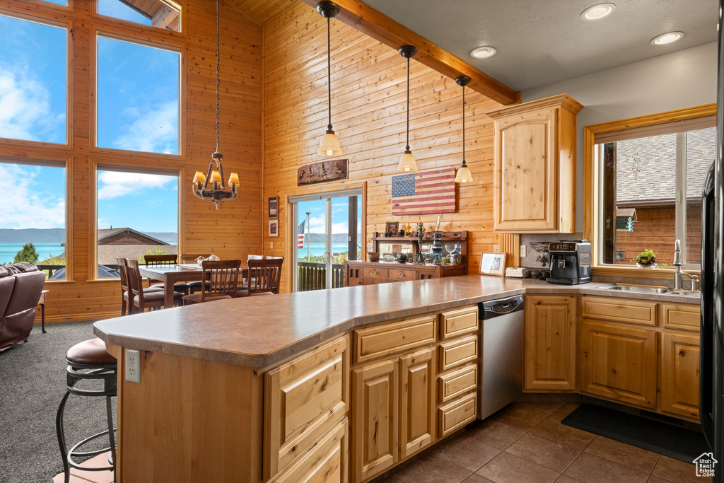 Kitchen featuring dishwasher, high vaulted ceiling, a peninsula, wood walls, and light brown cabinetry