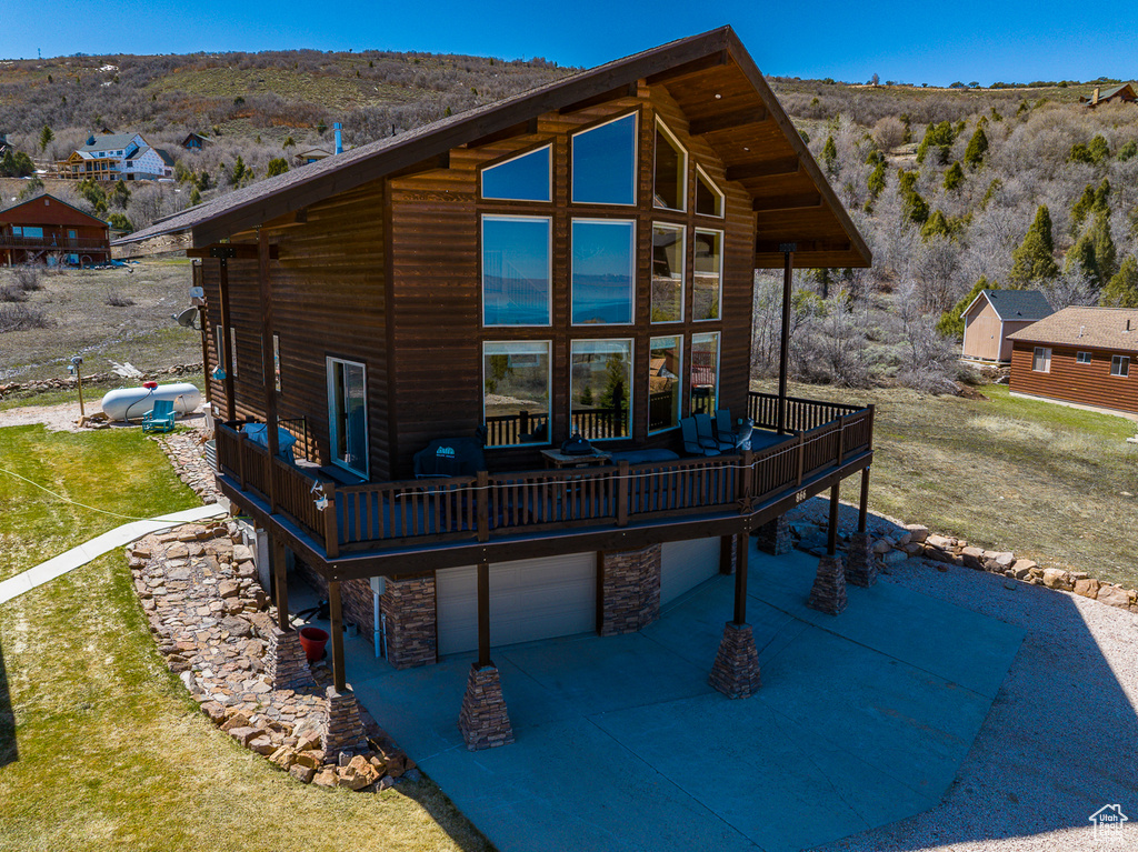 Back of property featuring a deck with mountain view, stone siding, and an attached garage