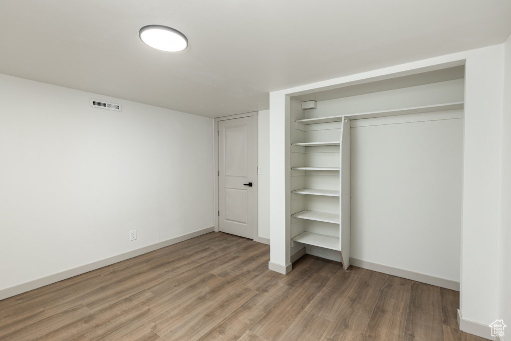 Unfurnished bedroom with wood finished floors, a closet, and baseboards