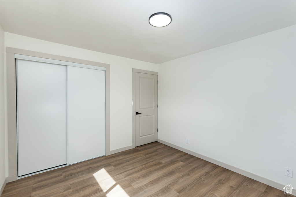 Unfurnished bedroom featuring wood finished floors, a closet, and baseboards