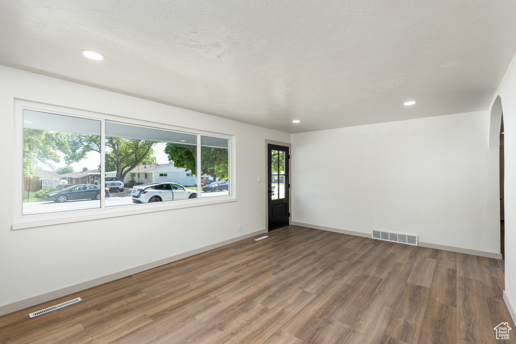 Spare room with healthy amount of natural light, wood finished floors, arched walkways, recessed lighting, and baseboards