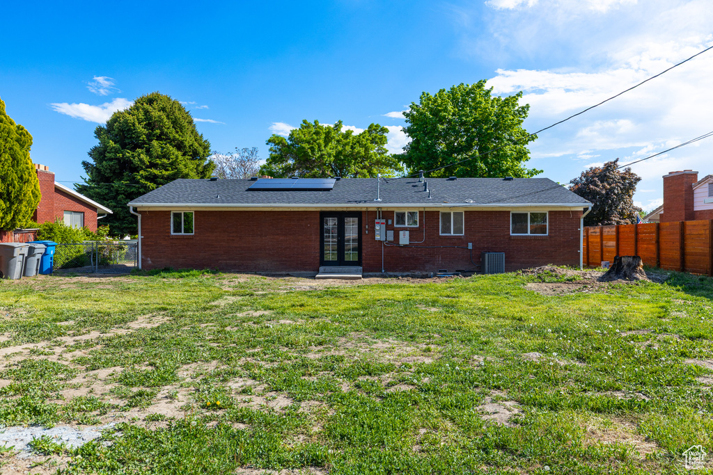 Rear view of property with french doors, roof mounted solar panels, a gate, central air condition unit, and brick siding