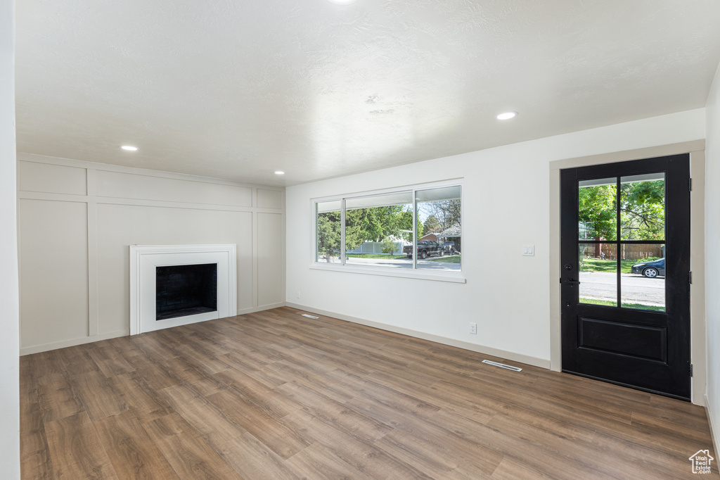 Unfurnished living room featuring wood finished floors, plenty of natural light, recessed lighting, a fireplace, and baseboards