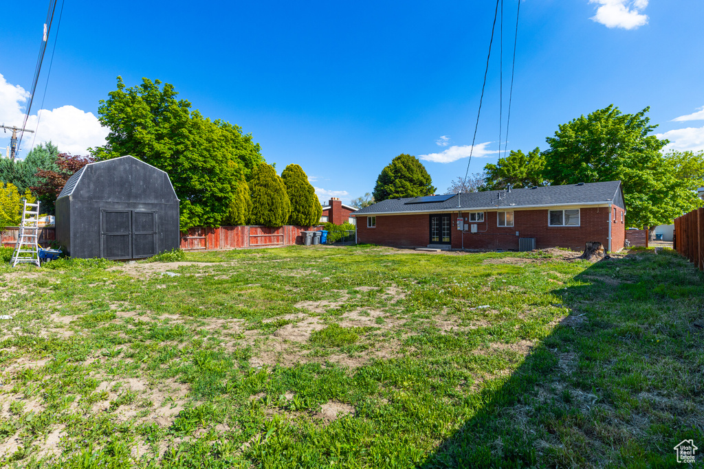 View of yard featuring a storage unit, french doors, an outdoor structure, and central AC unit