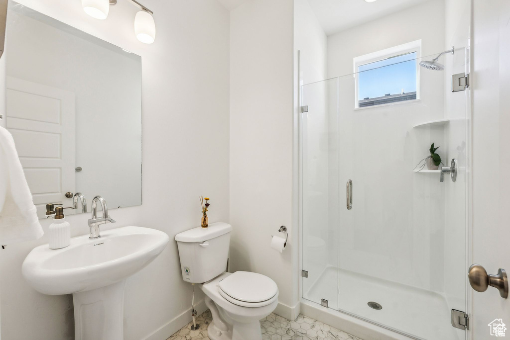 Bathroom with a stall shower, baseboards, toilet, and a sink