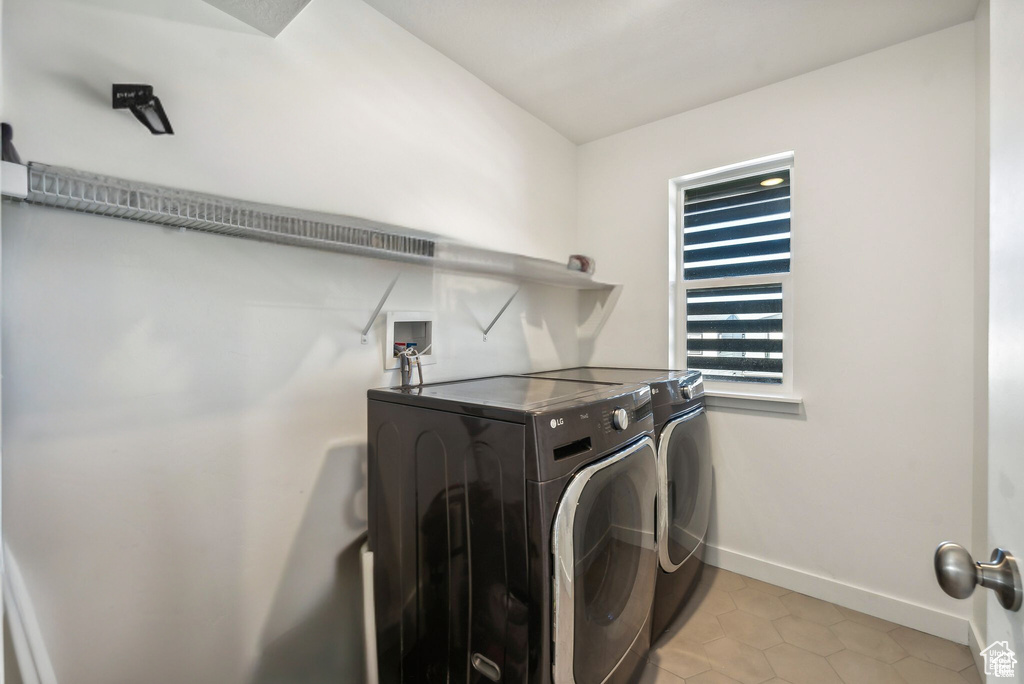 Laundry room featuring washer and clothes dryer, baseboards, and light tile patterned flooring