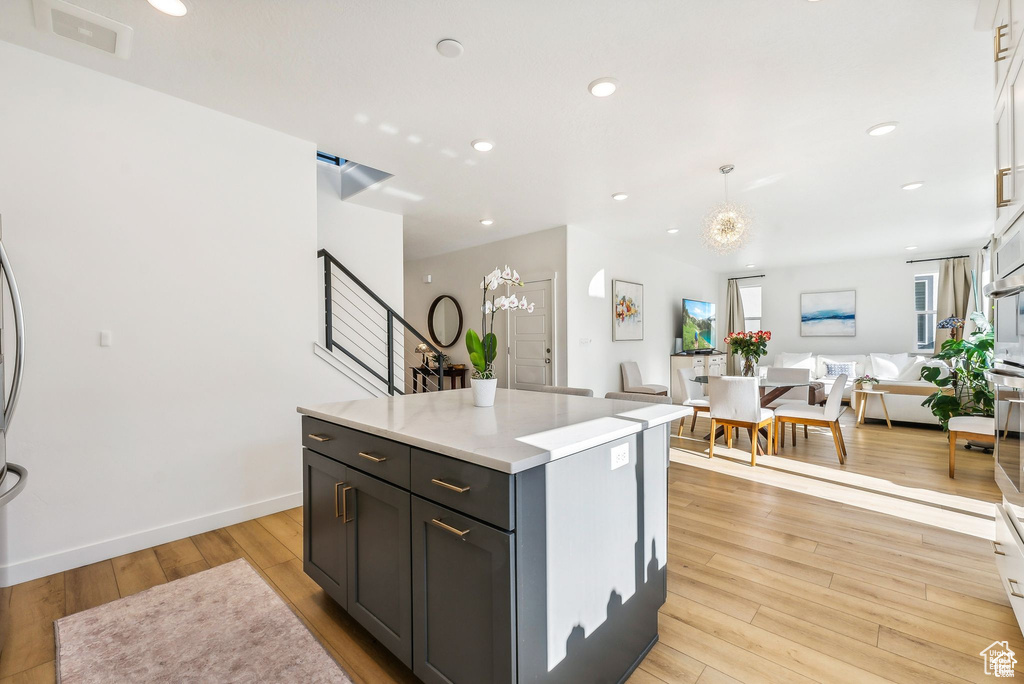 Kitchen with open floor plan, light wood-style flooring, light countertops, a center island, and recessed lighting
