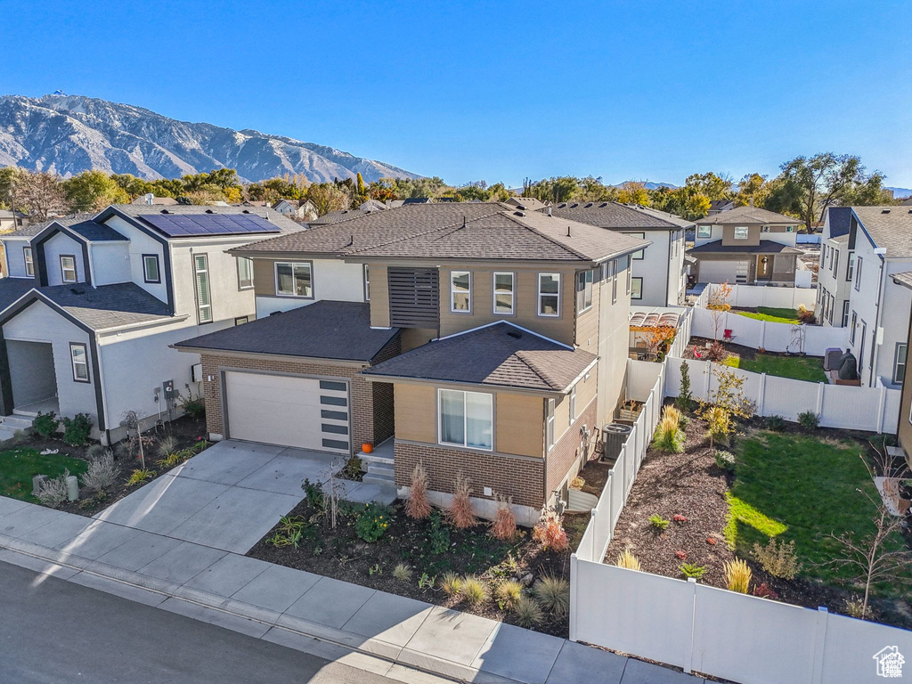 View of front of home with a residential view, fence, driveway, a mountain view, and roof with shingles