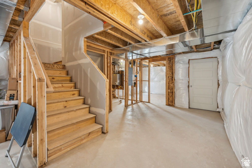 Unfinished below grade area with stairs and water heater