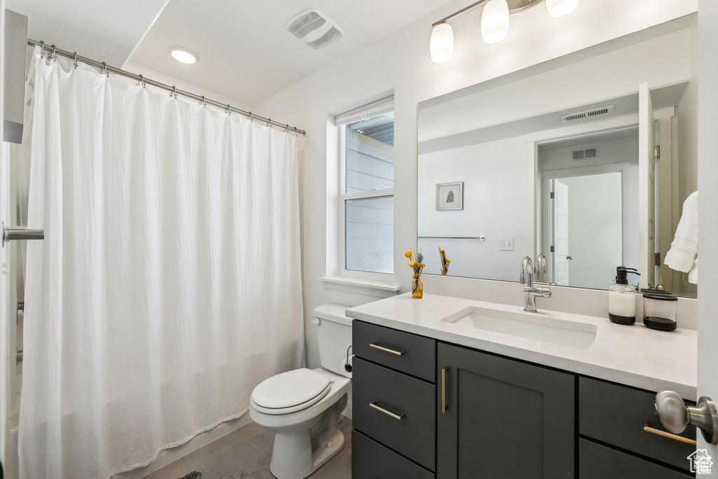 Bathroom featuring toilet, vanity, tile patterned flooring, and a shower with shower curtain